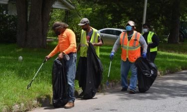 Workers pick up litter along Johnny W. Williams Road in Albany