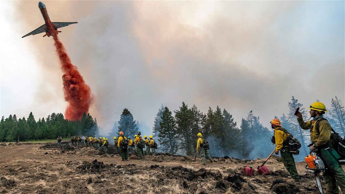 <i>Pete Caster/Lewiston Tribune/AP</i><br/>Wildland firefighters watch and take video with their cell phones as a plane drops fire retardant on Harlow Ridge above the Lick Creek Fire