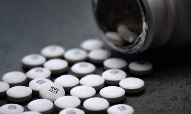 Bottle of white pills spilled on gray counter