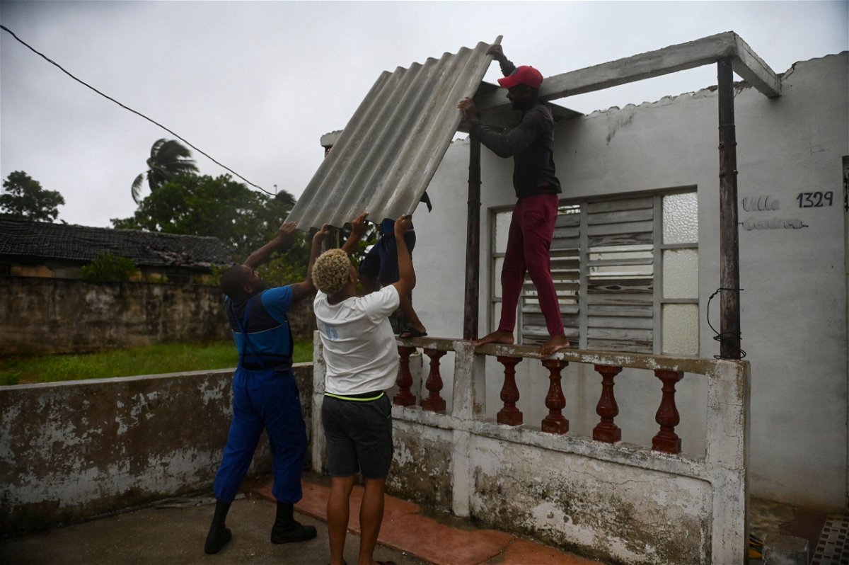 <i>Yamil Lage/AFP/Getty Images</i><br/>Men placed a corrugated metal sheet on the roof of a house in Batabano