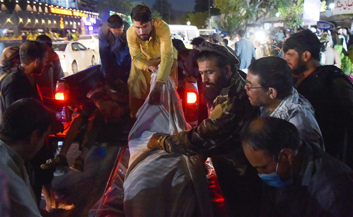 <i>Wakil Kohsar/AFP/Getty Images</i><br/>Volunteers and medical staff unload bodies from a pickup truck outside a hospital after the explosion outside the airport in Kabul on August 26.