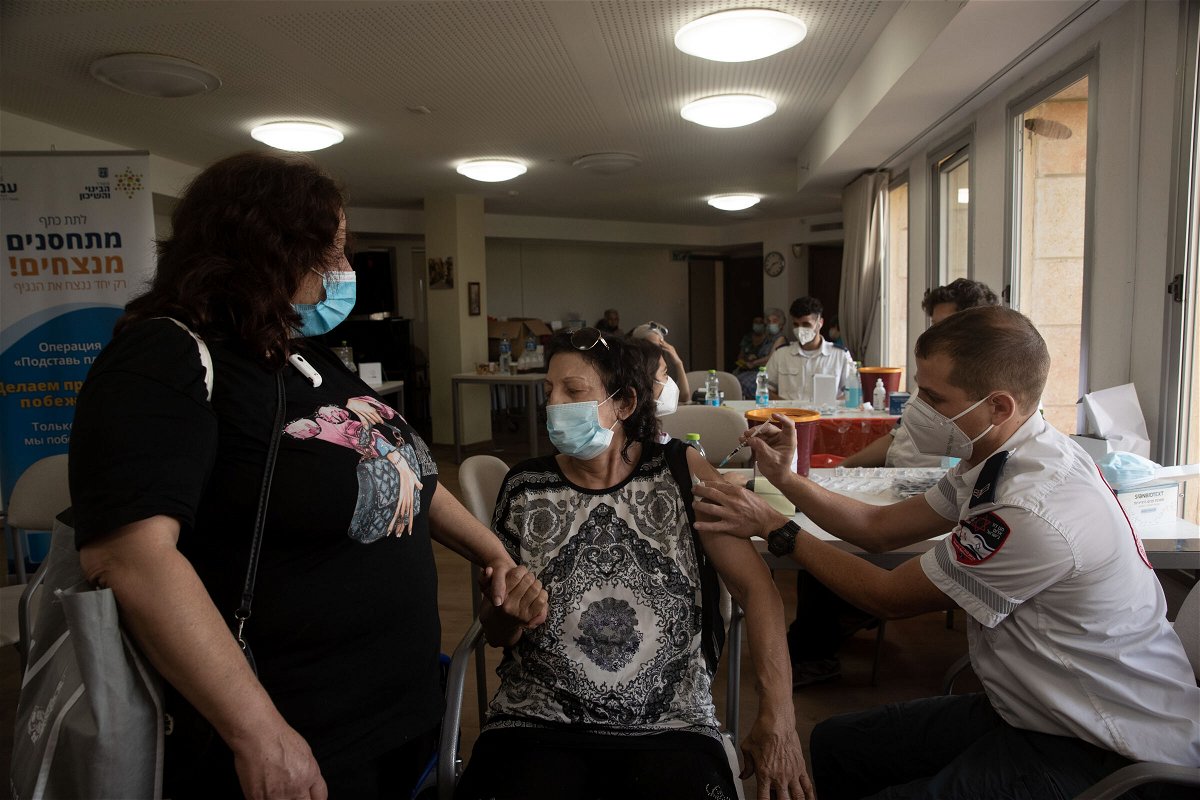 <i>Maya Alleruzzo/AP</i><br/>An Israeli woman receives a third coronavirus vaccine at a senior center in Jerusalem on Wednesday.