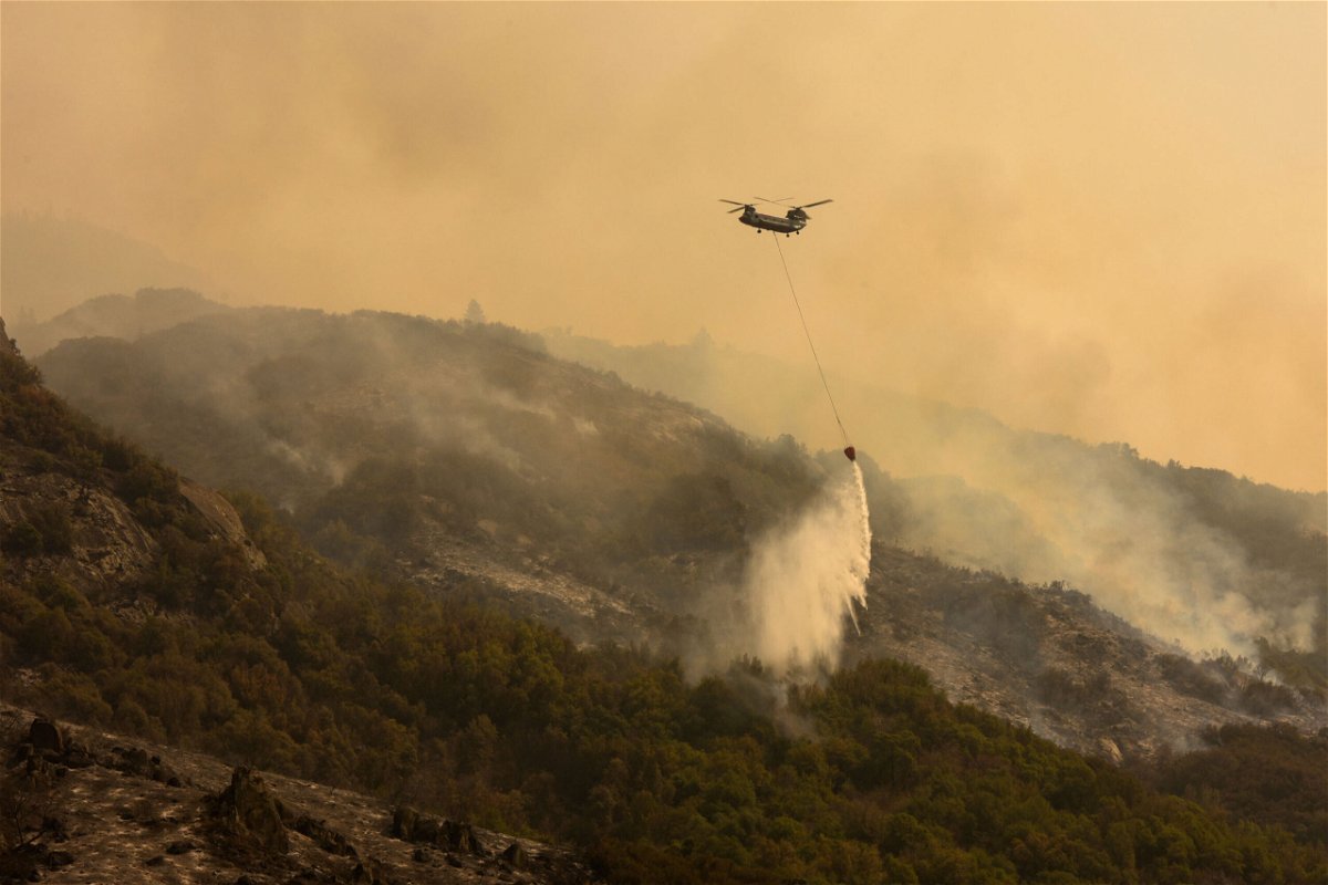 <i>PATRICK T. FALLON/AFP/Getty Images</i><br/>A Boeing CH-47 Chinook firefighting helicopter carries water to drop on the fire as smoke rises in the foothills along Generals Highway during a media tour of the KNP Complex fire in the Sequoia National Park near Three Rivers