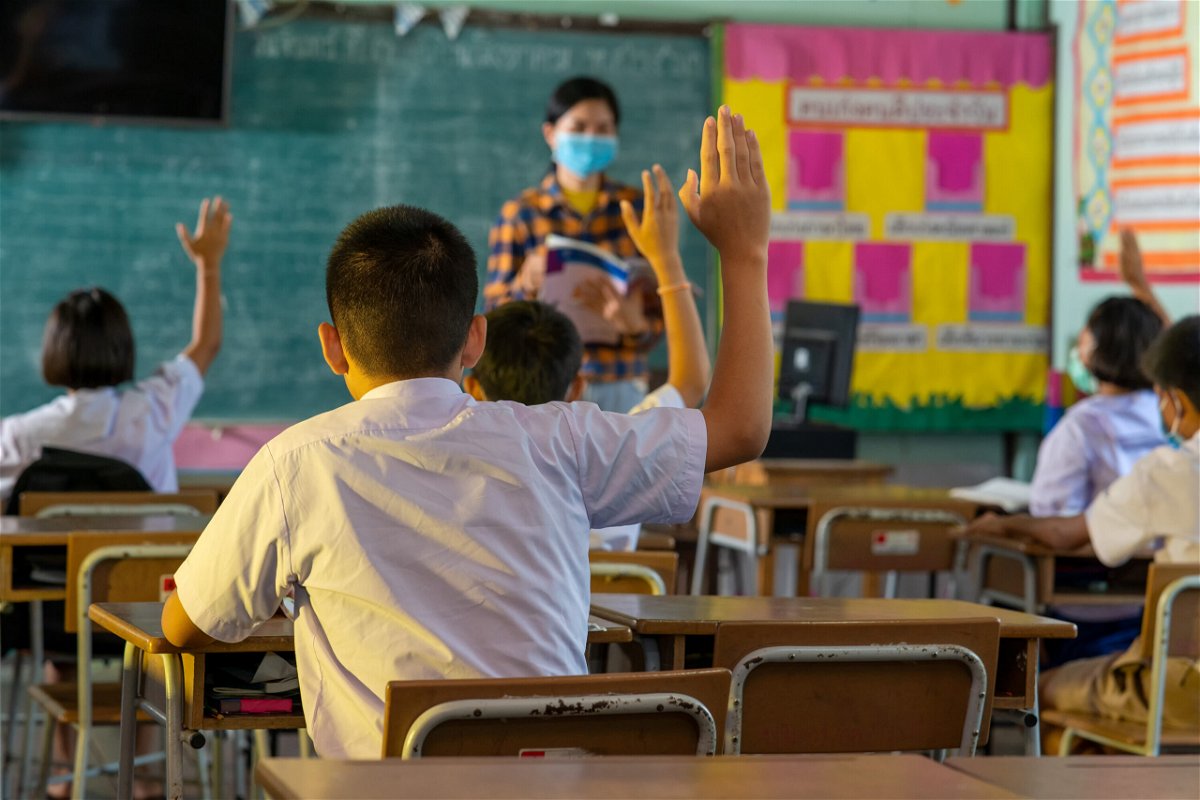 <i>Cavan Images/Getty Images</i><br/>Students and their teacher wear protective face masks in their elementary school.
