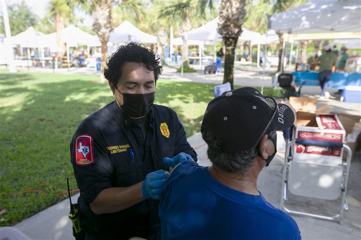<i>Denise Cathey/Brownsville Herald/AP</i><br/>Brownsville Fire Department lieutenant Rodrigo Rangel places a bandage over Homero Ortega's vaccine injection spot at the City of Brownsville's Department of Public Health's popup COVID-19 vaccine clinic