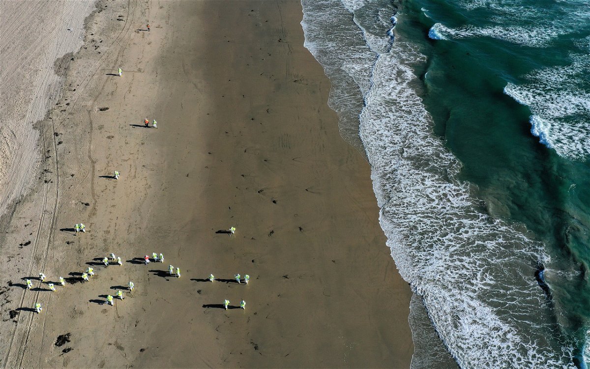 <i>Mario Tama/Getty Images</i><br/>Cleanup workers scour the sand in Huntington Beach