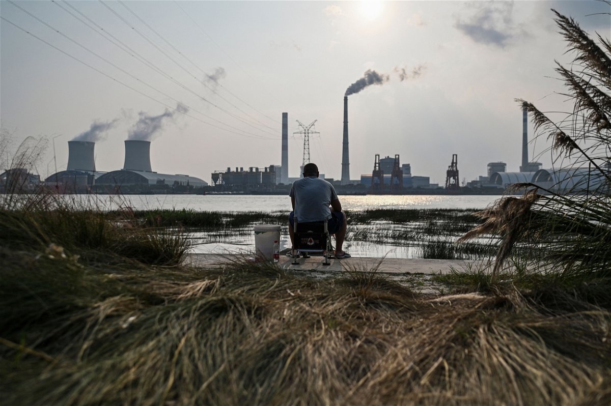 <i>Hector Retamal/AFP/Getty Images</i><br/>China plans to cut its reliance on fossil fuels to below 20% by 2060. An angler is seen fishing along the Huangpu river across the Wujing Coal-Electricity Power Station in Shanghai on September 28