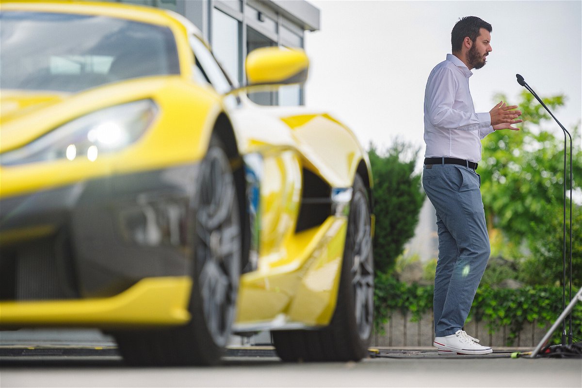 <i>Petar Santini/Bloomberg/Getty Images</i><br/>Rimac delivers a speech beside a Rimac Nevera electric supercar outside the company's Croatian factory in July.