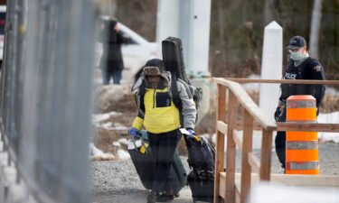 An asylum seeker crosses the border from New York into Canada followed by a Royal Canadian Mounted Police (RCMP) officer in Hemmingford
