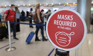 A sign about the federal mask requirement is seen as travelers prepare to check in at Miami International Airport on February 01