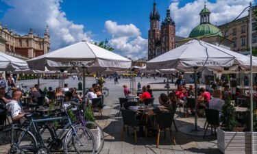 People enjoy drinks and food on an outdoor garden bar at Krakow's UNESCO listed Main Square on May 15 in Krakow