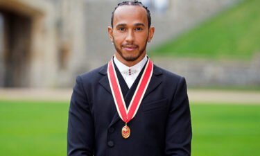 Mercedes' British F1 driver Lewis Hamilton poses with his medal after being appointed as a Knight Bachelor for services to motorsports