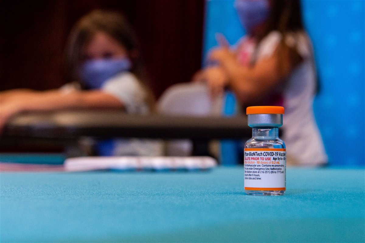 <i>JOSEPH PREZIOSO/AFP/Getty Images</i><br/>A vial of the new children's dose of the Pfizer-BioNTech Covid-19 vaccine sits in the foreground as children play in a hospital room waiting to be able to receive the vaccine at Hartford Hospital in Hartford