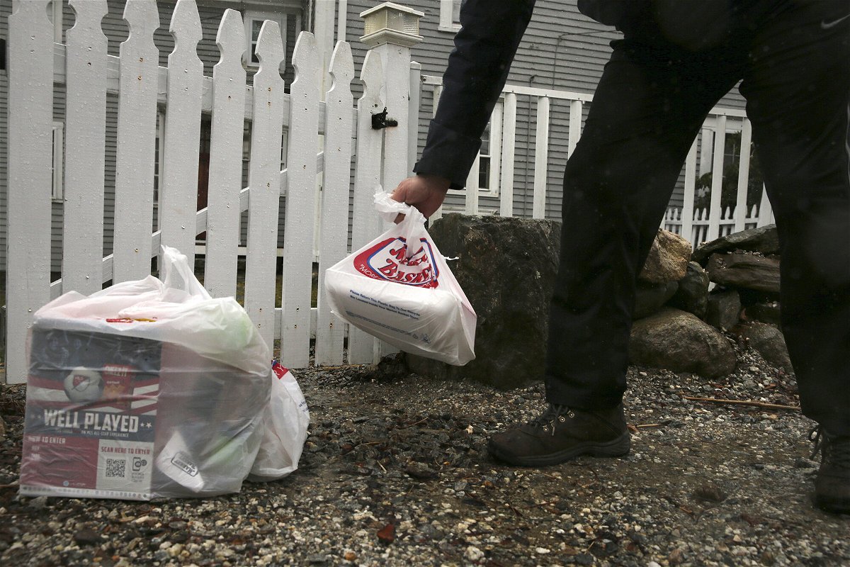 <i>Charles Krupa/AP</i><br/>An Instacart worker leaves groceries at the gate of a home in New Hampshire in April 2020.