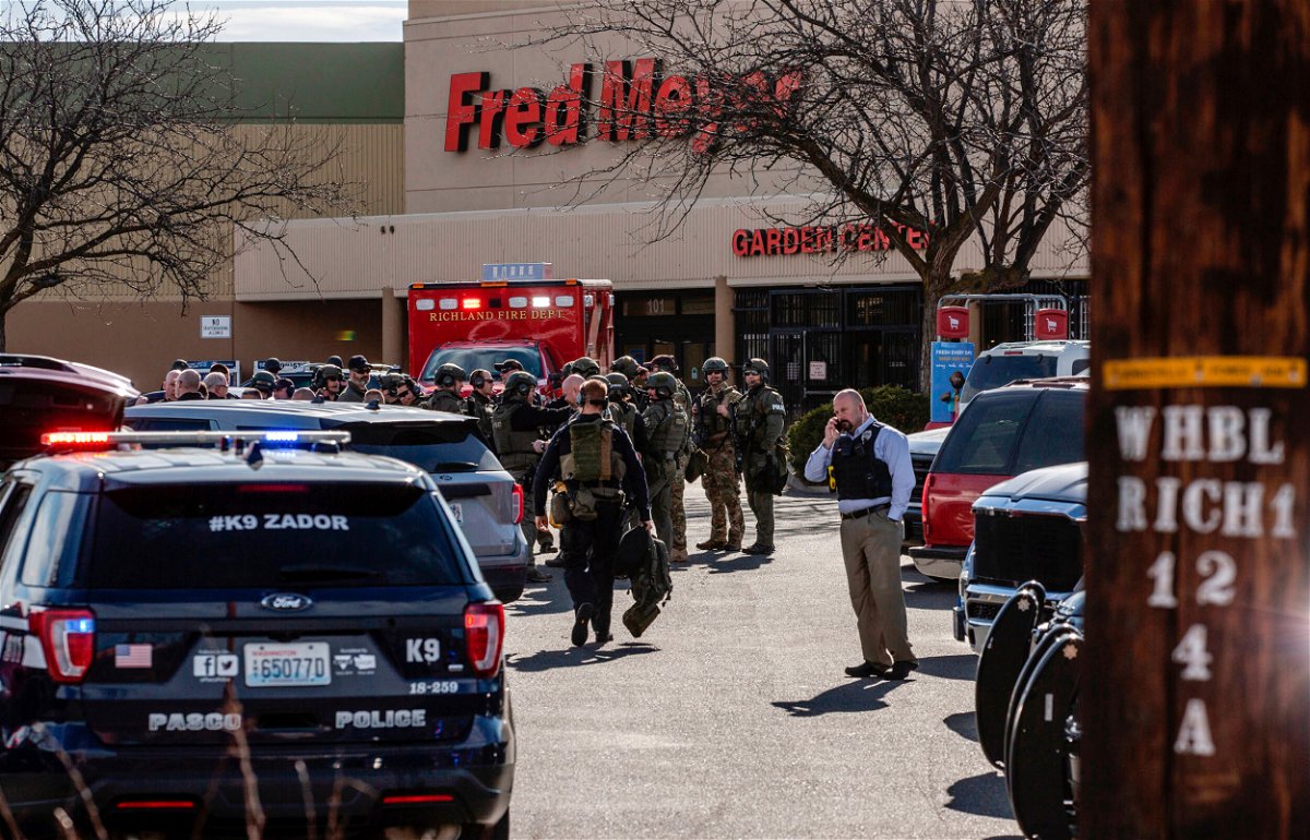 <i>Jennifer King/The News Tribune/AP</i><br/>Emergency responders gather at the store as the hunt for a suspect continued Monday.