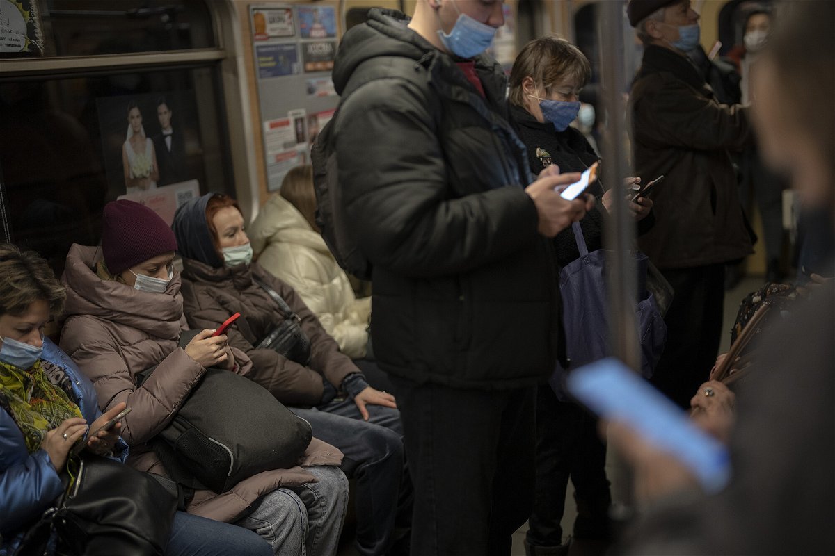 <i>Emilio Morenatti/AP</i><br/>Commuters look at their phones as they travel in a local train in Kyiv