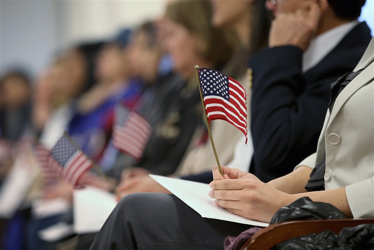 <i>John Moore/Getty Images</i><br/>Immigrants hold flags while waiting for a naturalization ceremony to become U.S. citizens at the district office of U.S. Citizenship and Immigration Services (USCIS) on January 28