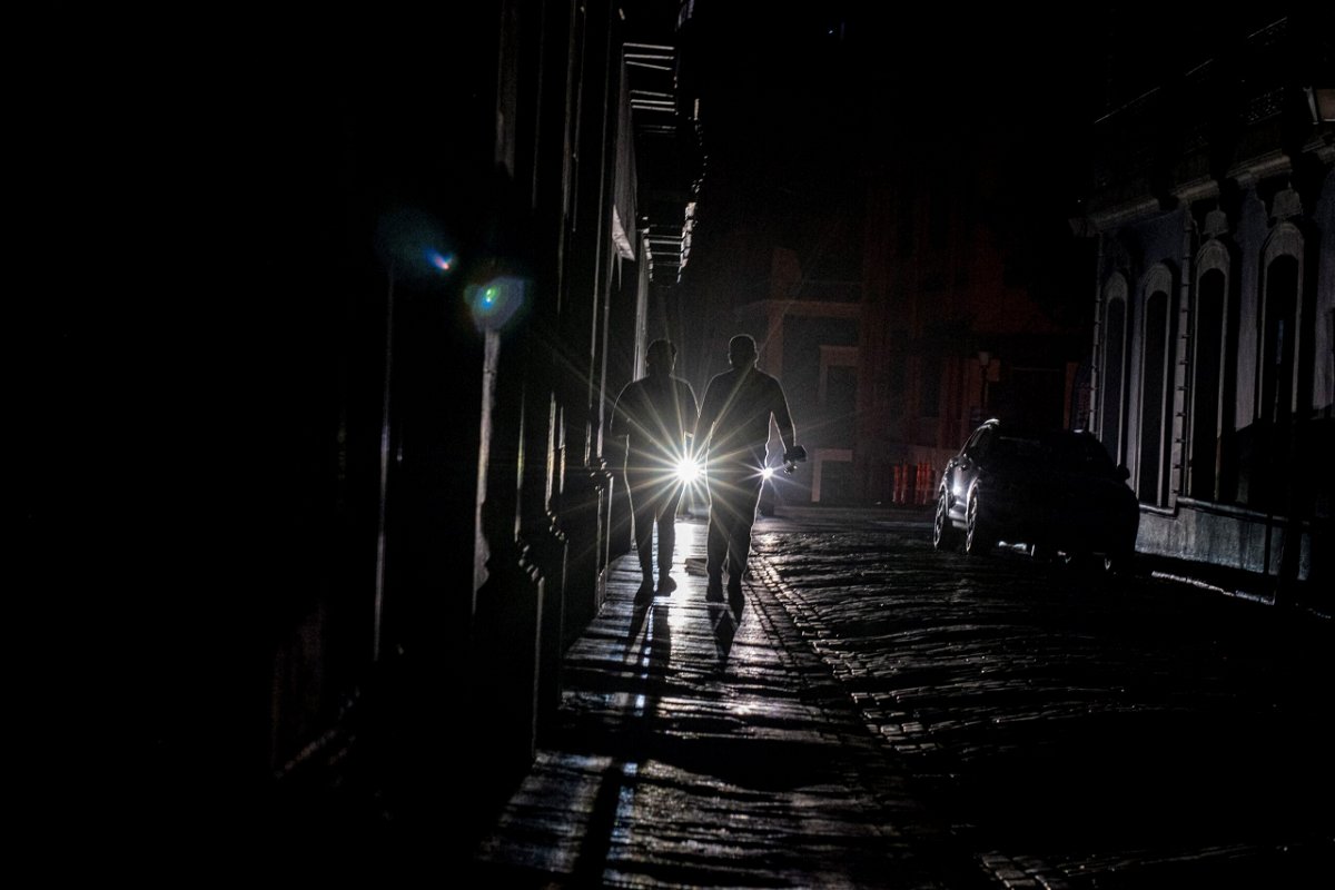 <i>RICARDO ARDUENGO/AFP/Getty Images</i><br/>A vehicle's headlights are seen as people walk on a dark street in San Juan