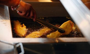 A chef turns a piece of fried fish in the fryer as it gets cooked