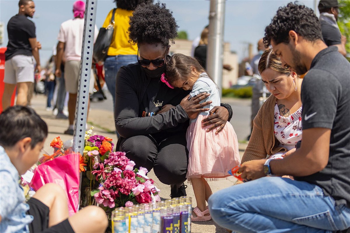 <i>Lauren Petracca for CNN</i><br/>A young girl comforts a person crying on May 15 at a memorial outside of a Tops Friendly Market where a mass shooter killed 10 people and wounded three.