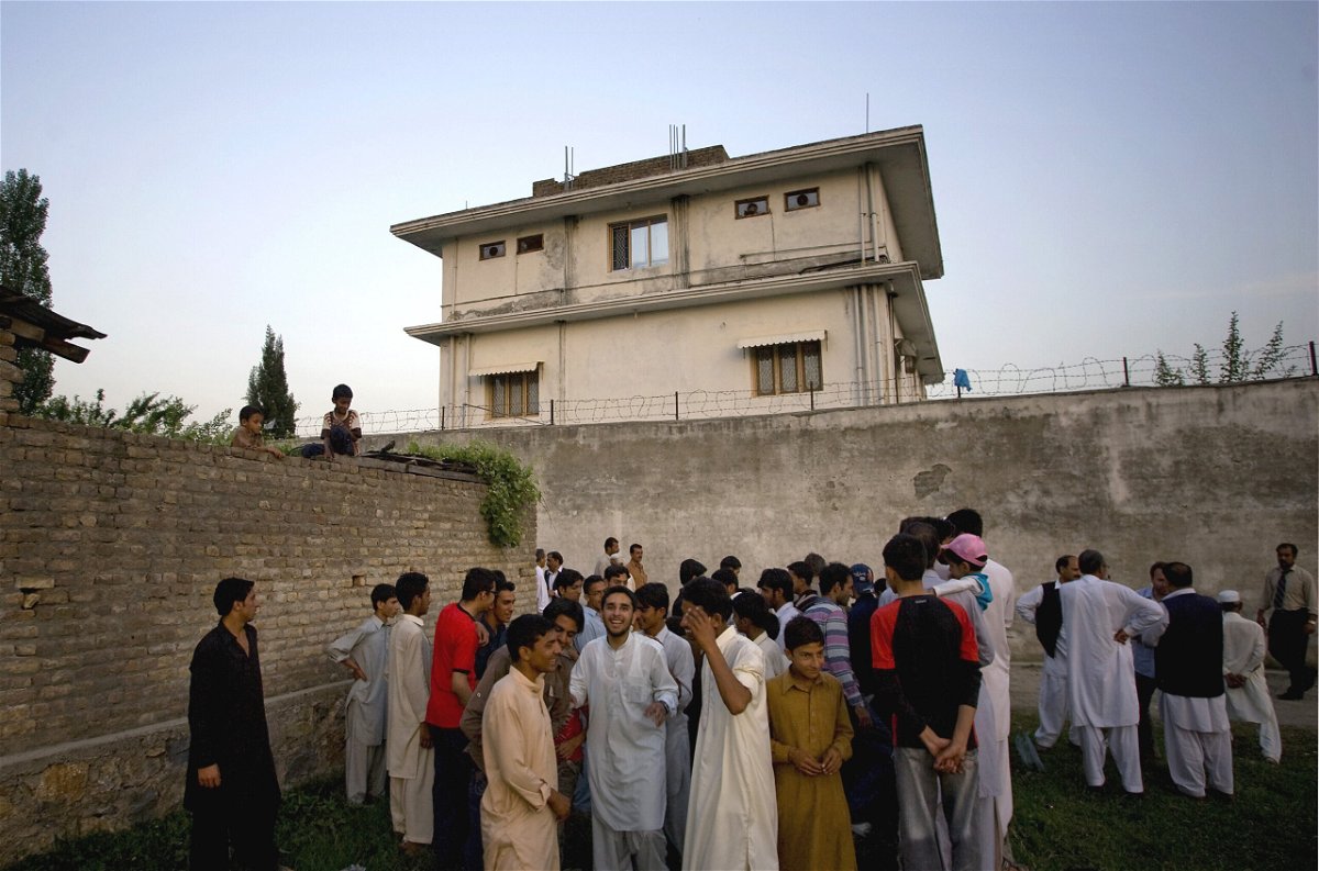 <i>Anjum Naveed/AP</i><br/>Residents gather outside a house
