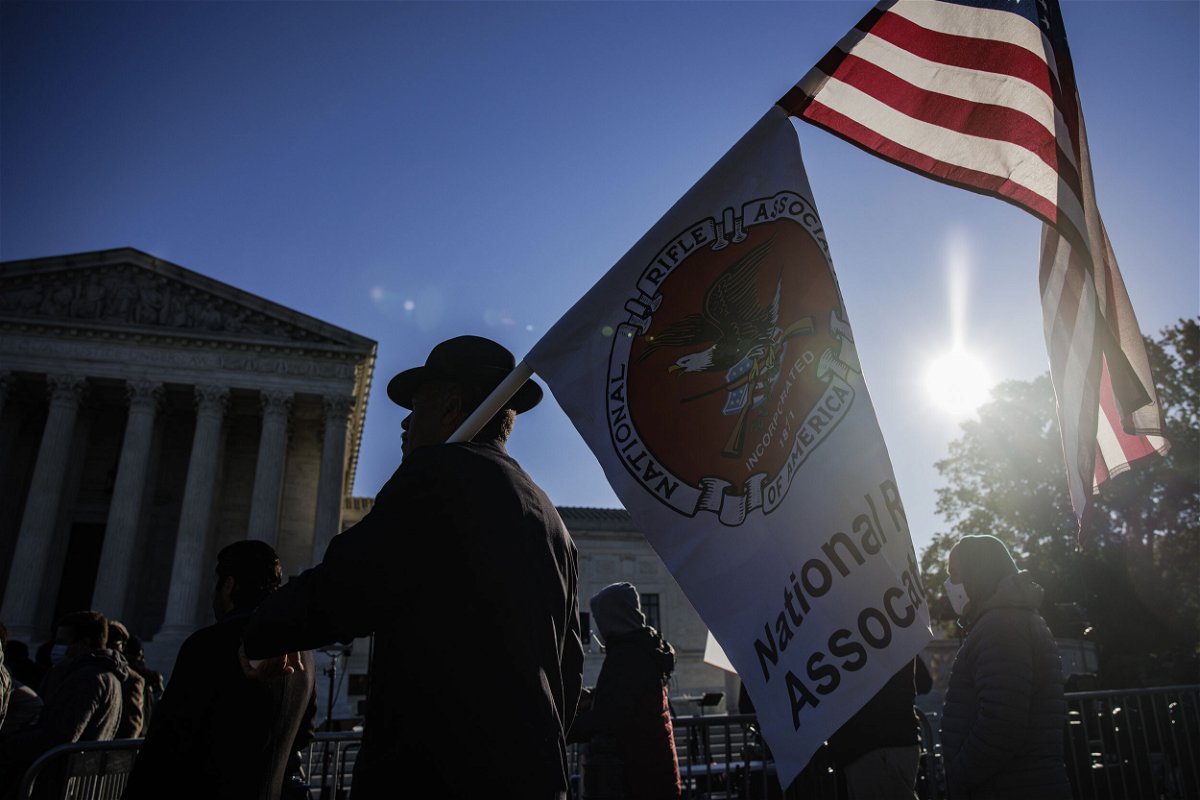 <i>Samuel Corum/Bloomberg/Getty Images</i><br/>A demonstrator holds American and National Rifle Association flags outside the Supreme Court in November 2021.