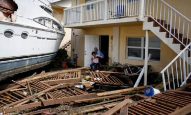 A man helps a woman next to a damaged boat amid a downtown condominium after Hurricane Ian caused widespread destruction in Fort Myers