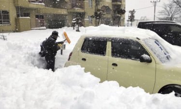 A man shovels snow off a car in Hokkaido