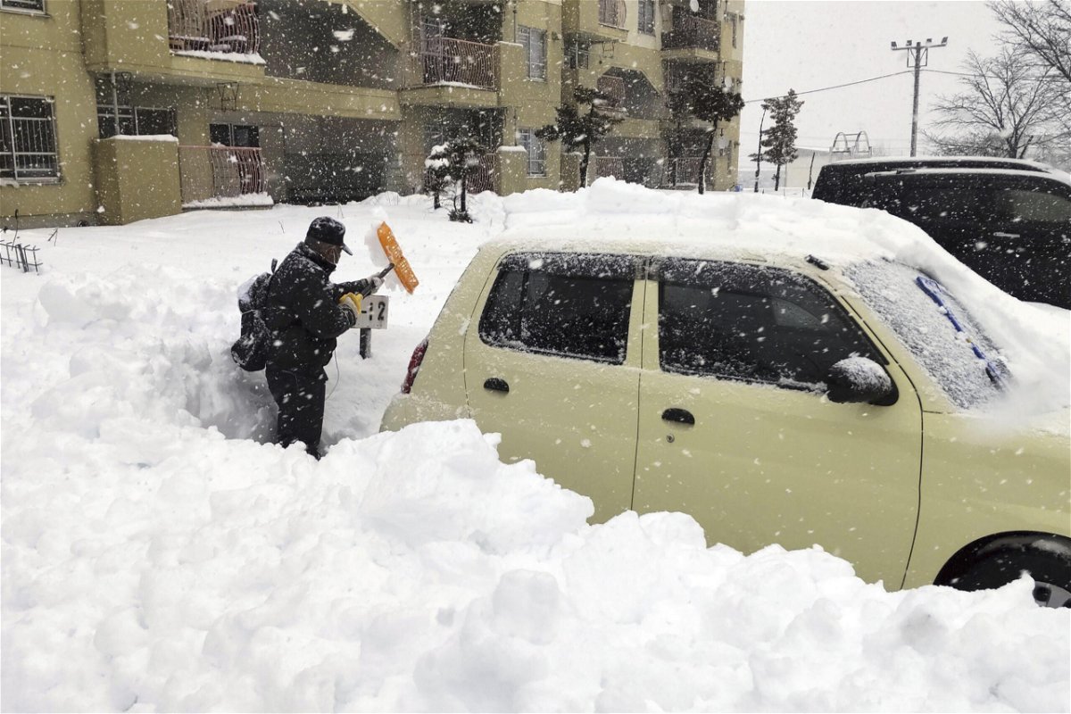 <i>Kyodo News/AP</i><br/>A man shovels snow off a car in Hokkaido