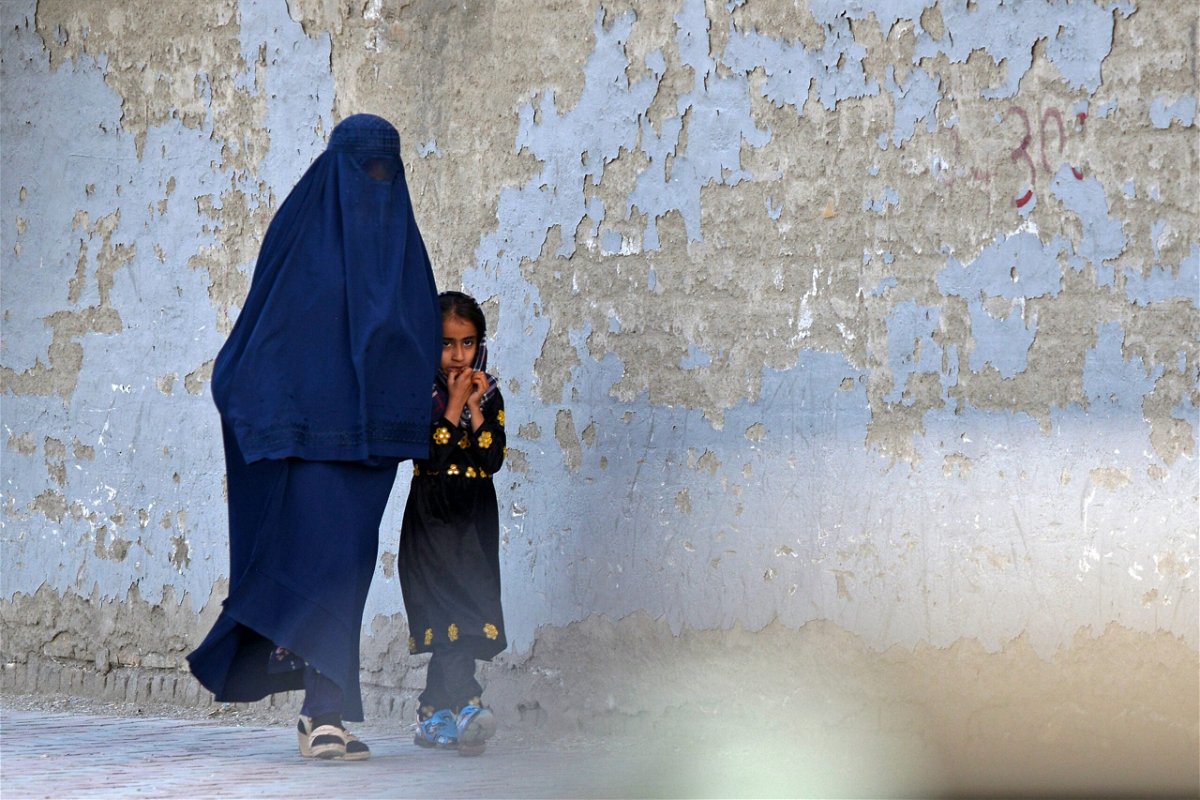 <i>AHMAD SAHEL ARMAN/AFP/AFP via Getty Images</i><br/>A burqa-clad woman walks with a girl along a street in Kabul on May 7. The Taliban imposed some of the harshest restrictions on Afghanistan's women since they seized power