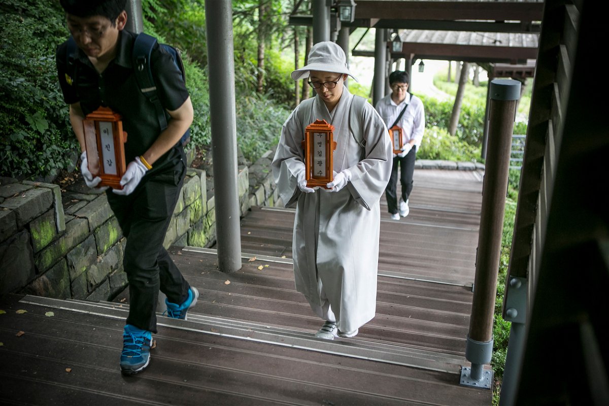 <i>Jean Chung/Getty Images</i><br/>Staff and a volunteer Buddhist nun of a nonprofit organization carry the name tablets of people who died 