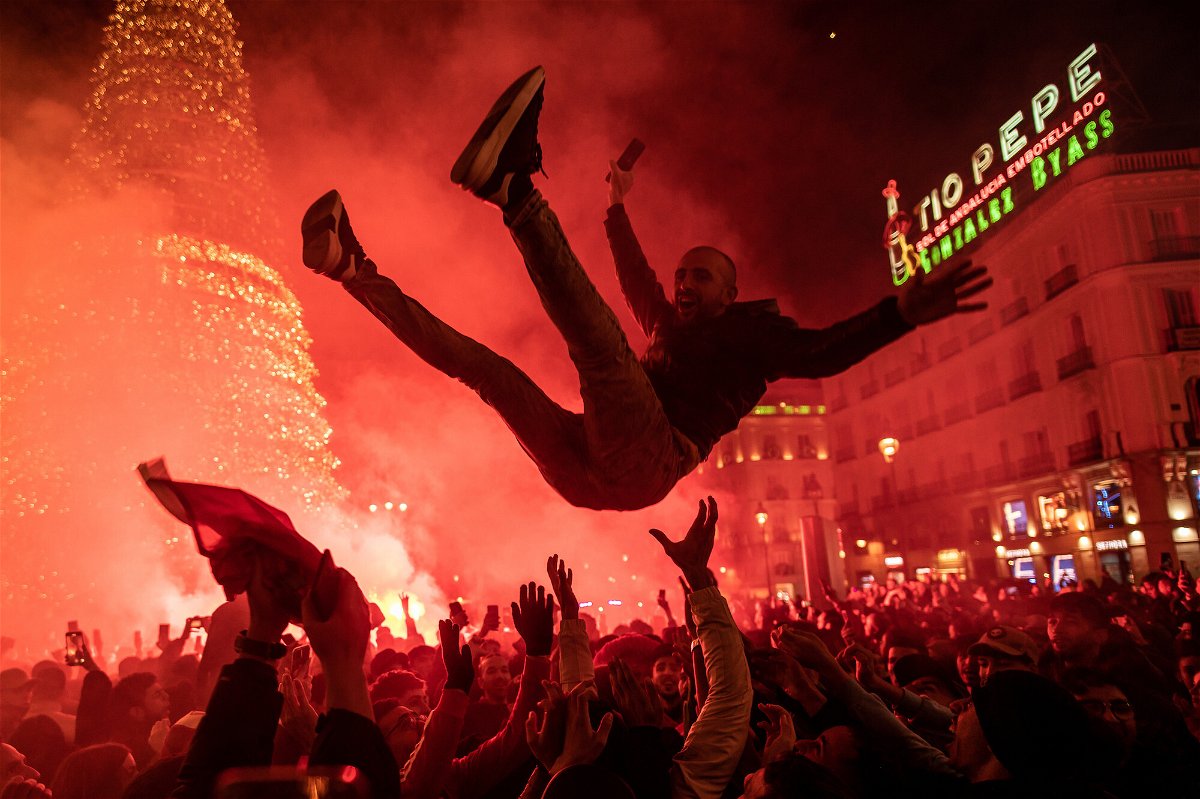 <i>Marcos del Mazo/LightRocket/Getty Images</i><br/>A man flies over the crowd as fans of the Moroccan soccer team celebrate in Madrid.