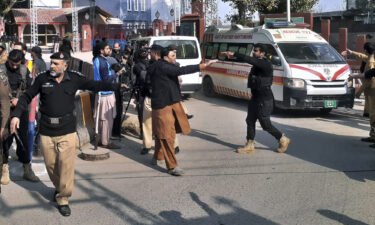 Police officers clear the route for ambulances carrying wounded people from the scene in Peshawar