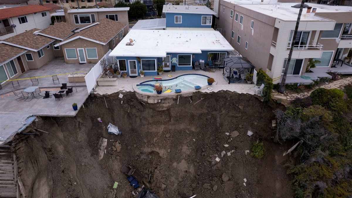 <i>Mike Blake/Reuters</i><br/>A backyard pool is left hanging on a cliffside Thursday after torrential rain hit the beachfront town of San Clemente