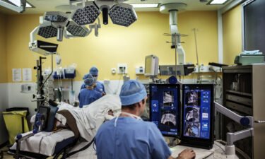 A surgeon sitting in front of screens of a Focal One device performs a robot-assisted prostate tumorectomy using ultrasound imaging on April 10