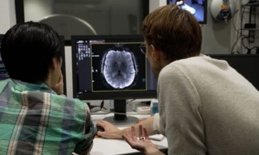 Assistant Professor Alexander Huth (right) and PhD Student Jerry Tang review brain imaging from CNN Correspondent Donie O'Sullivan.