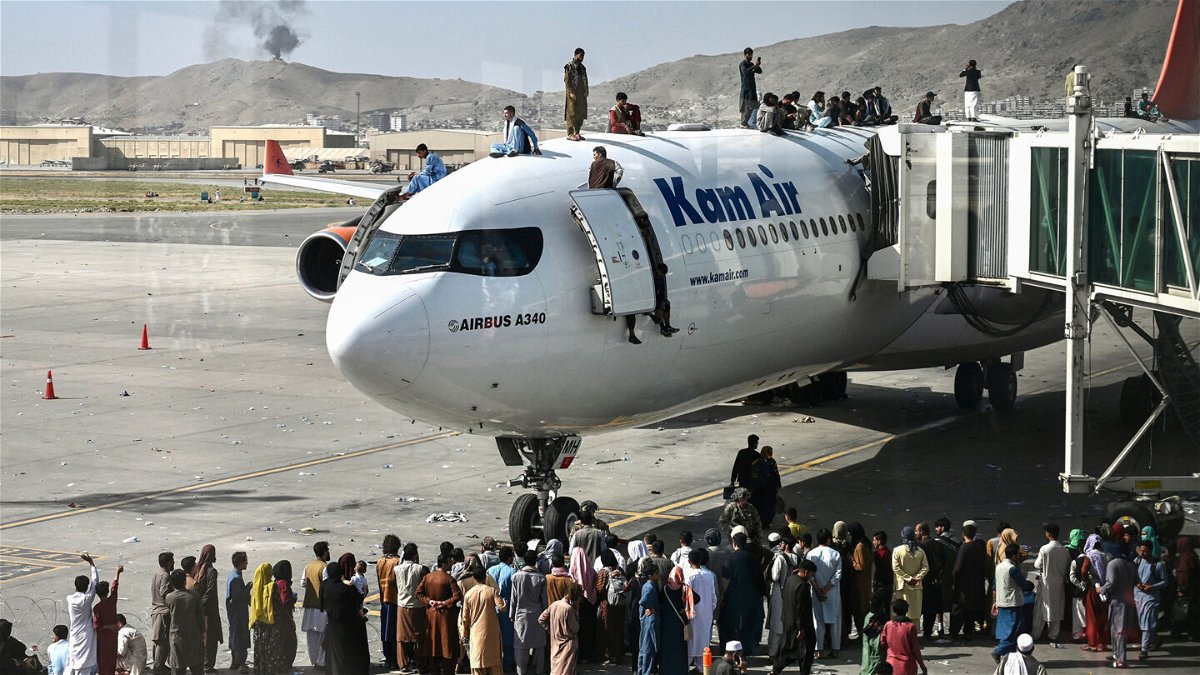 <i>Wakil Kohsar/AFP/Getty Images</i><br/>Afghans climb atop a plane as they wait at the Kabul airport on August 16