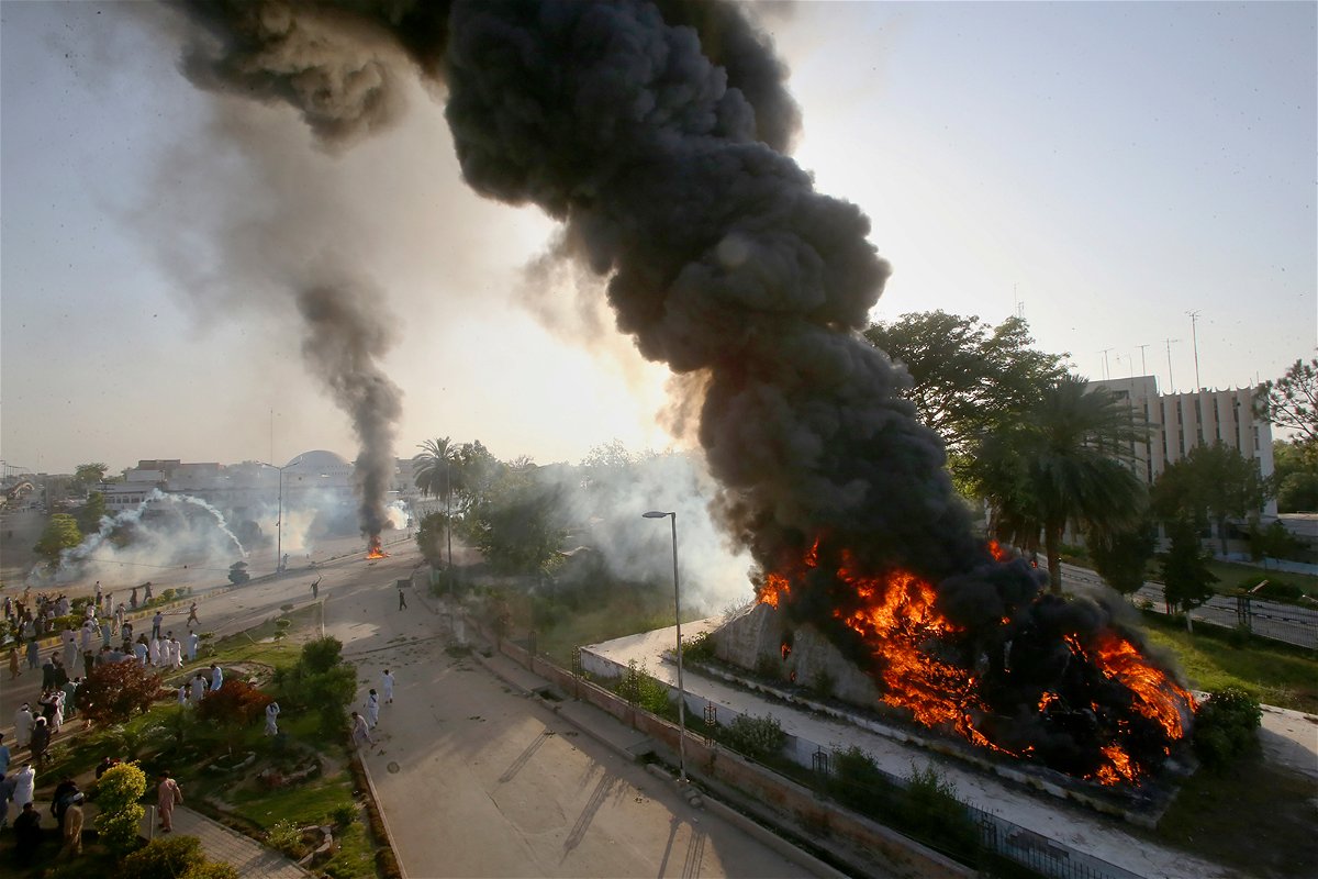 <i>Muhammad Sajjad/AP</i><br/>Smoke rises from fires set by angry supporters of Pakistan's former Prime Minister Imran Khan as police fire tear gas to disperse them during a protest in Peshawar on May 9.