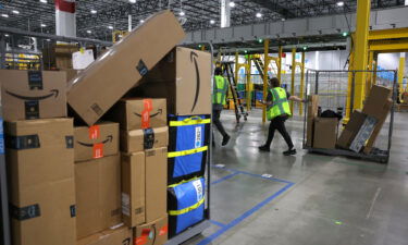 An Amazon worker moves a cart filled with packages at an Amazon delivery station in November 2022 in Alpharetta