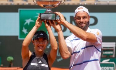 Japan's Miyu Kato and Tim Puetz hold the trophy after winning the mixed doubles final at the French Open.