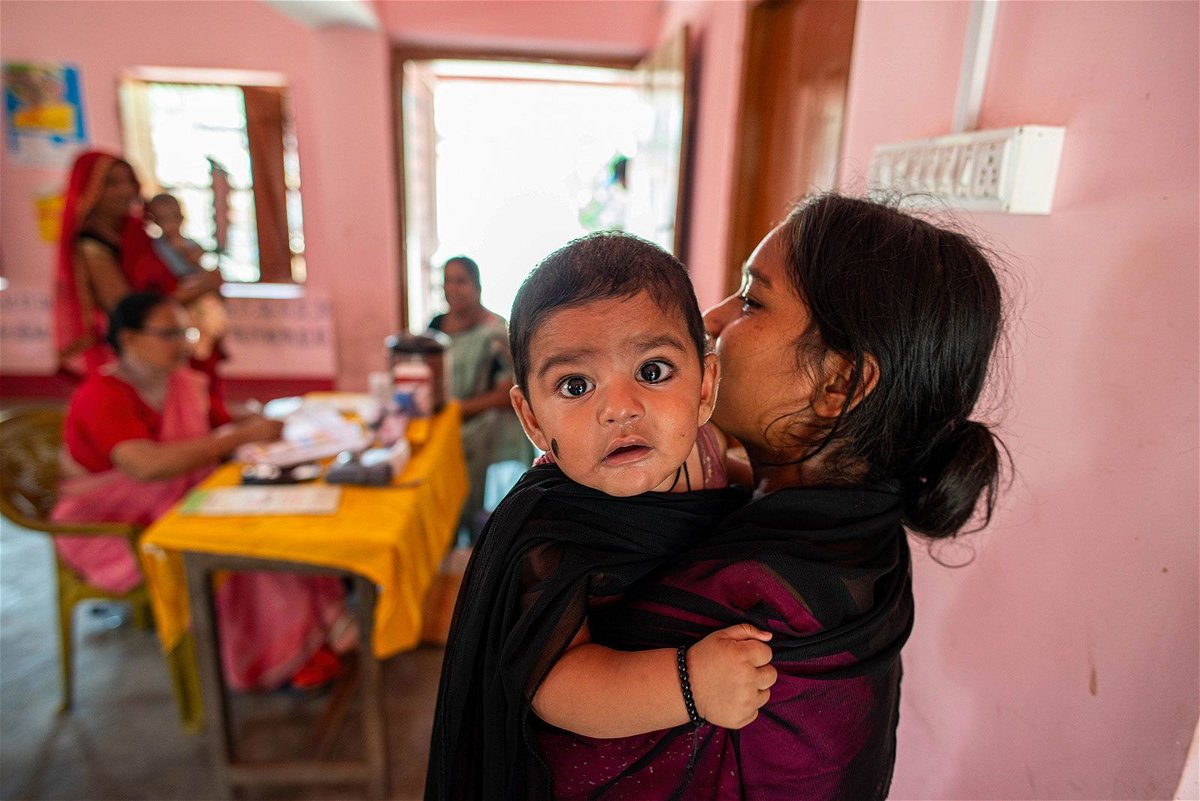 A woman carrying her young child takes part in a monthly child vaccination camp June 19 in Brindaban village