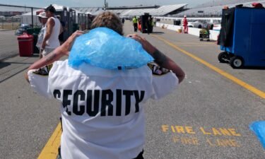Track security officer Patty Patterson carries a bag of ice on her shoulders as she walks back to her post during a NASCAR Cup Series auto race practice at New Hampshire Motor Speedway in Loudon