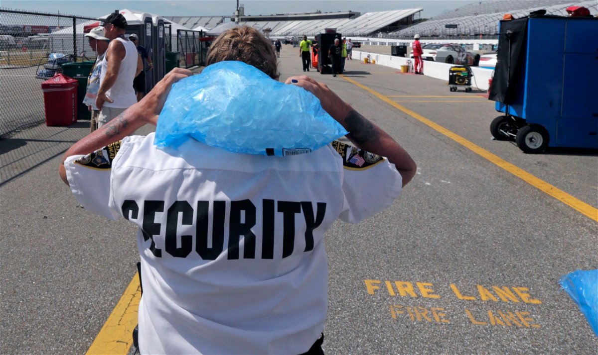 Track security officer Patty Patterson carries a bag of ice on her shoulders as she walks back to her post during a NASCAR Cup Series auto race practice at New Hampshire Motor Speedway in Loudon