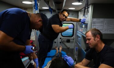 A firefighter EMT team treats a migrant woman suffering from heat exhaustion in the border community of Eagle Pass