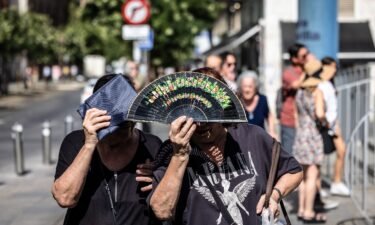 People shield themselves from the sun during high temperatures in Seville