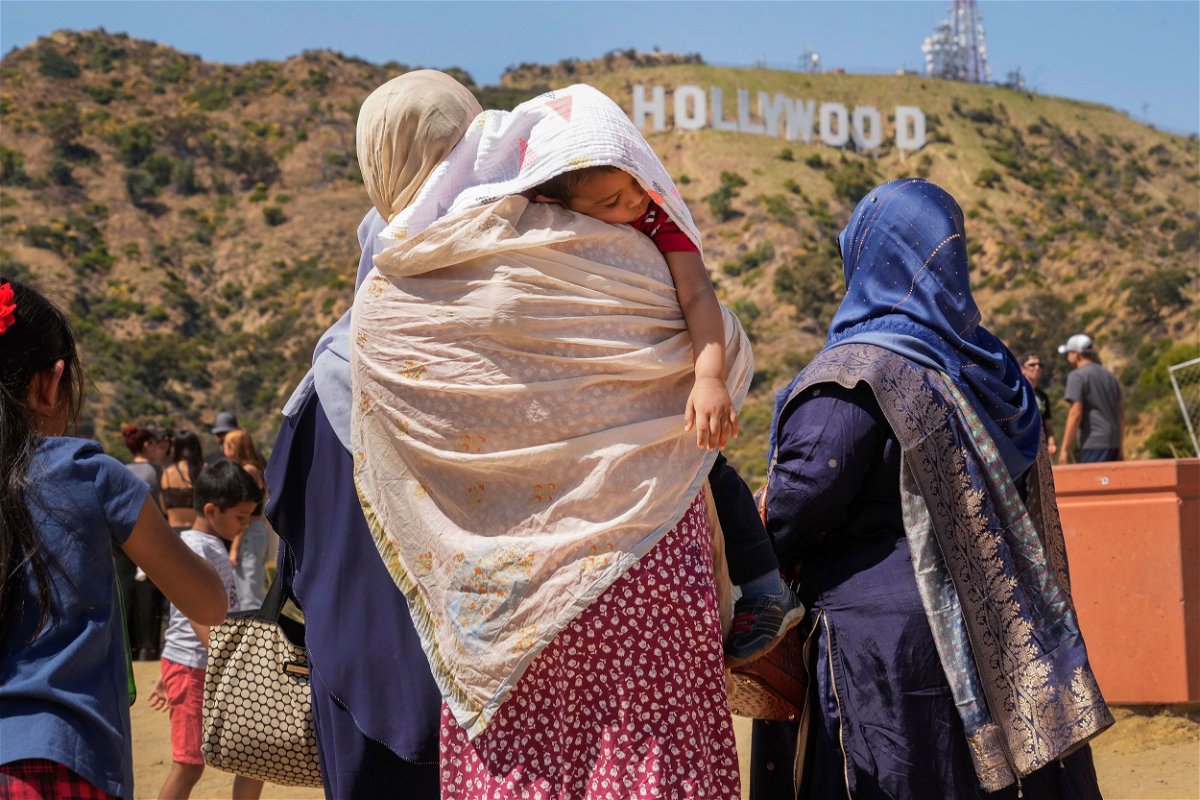 Tourists protect a sleeping child from the sun as they visit the Hollywood sign landmark in Los Angeles on July 12.