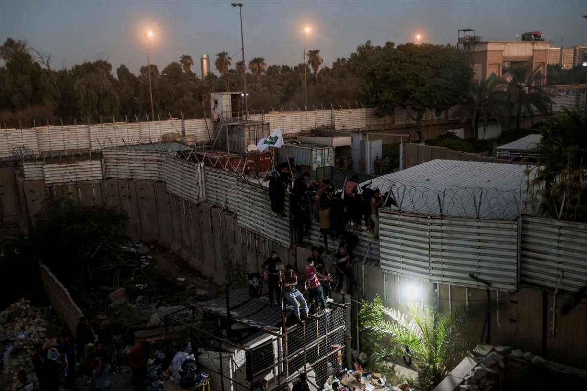 Protesters climb a fence near the Swedish embassy in Baghdad on July 20.