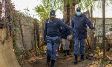 South African police officers remove gas cylinders used by illegal gold miners in the Angelo Informal Settlement in Boksburg