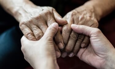 Parkinson and Alzheimer female senior elderly patient with caregiver in hospice care. Doctor hand with stethoscope check up older woman people. Old aging person seeing medical physician in hospital.