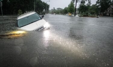 An SUV is stranded in a ditch along a stretch of street flooding during a severe storm Thursday in Spring